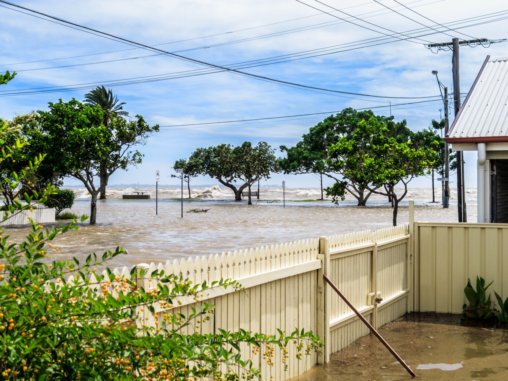 The sea washing over the sea wall and flooding the street in Sandgate, Brisbane