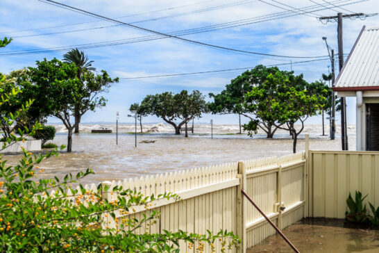 The sea washing over the sea wall and flooding the street in Sandgate, Brisbane